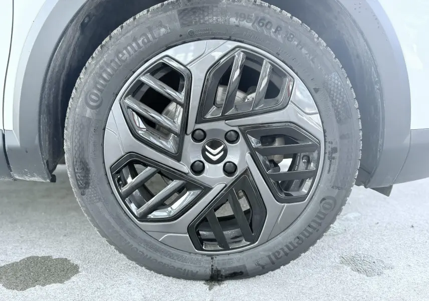Gros plan sur la roue avant droite blanche d'une Citroën C4 2023 avec jante alliage noire et grise au design géométrique.