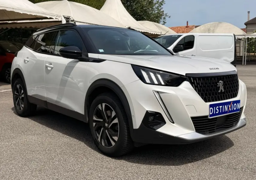 Peugeot 2008 blanc en 3/4 avant droit, avec calandre noire et jantes alliage distinctives, stationné en extérieur.