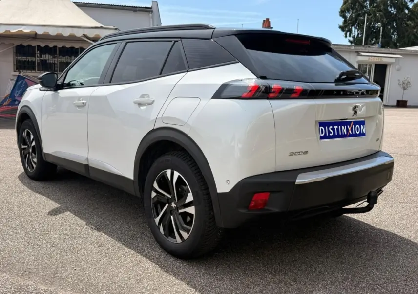 Vue 3/4 arrière droite d'un Peugeot 2008 blanc avec toit noir et feux arrière à griffes rouges distinctifs.