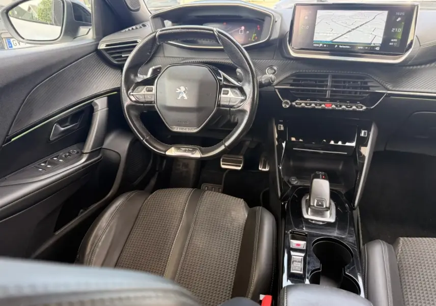 Vue intérieure de face du poste de conduite du Peugeot 2008 blanc, avec volant compact et écran tactile central lumineux.