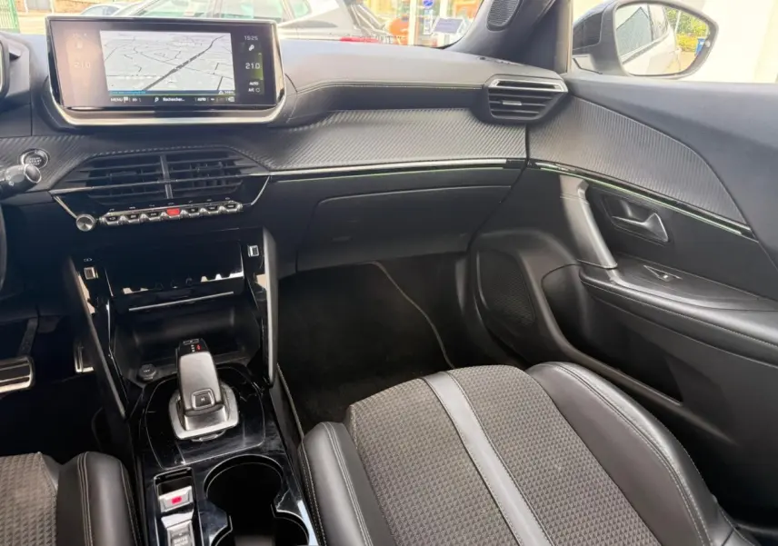 Vue intérieure côté passager du Peugeot 2008 blanc, mettant en valeur la console centrale moderne et l'écran tactile intégré.