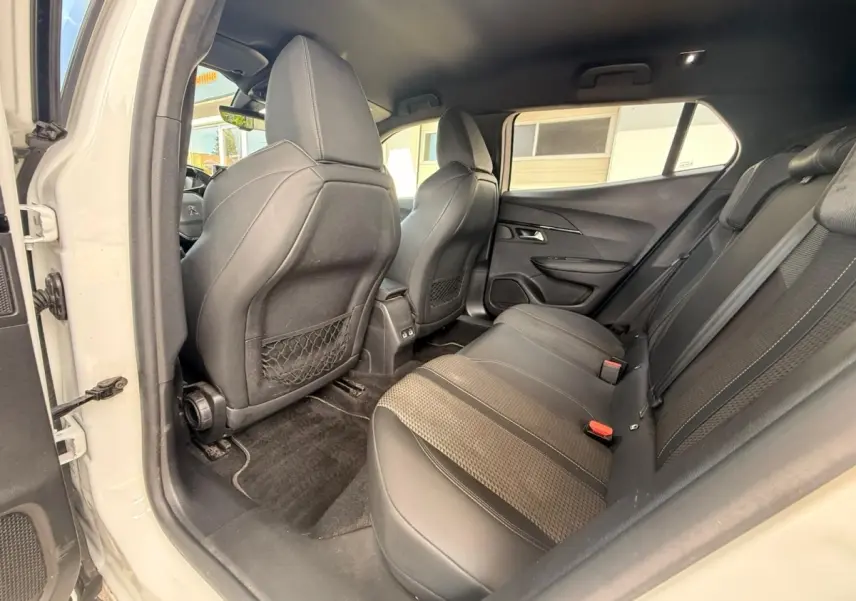 Vue intérieure côté gauche arrière du Peugeot 2008 blanc, mettant en valeur la banquette tri-matière et les filets au dos des sièges avant.