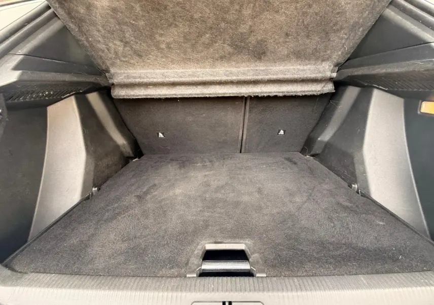 Vue intérieure du coffre ouvert d'un Peugeot 2008 blanc, montrant le plancher et la moquette noire du compartiment.