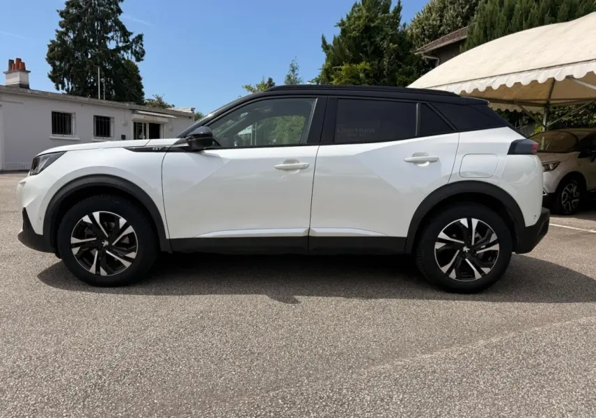 Peugeot 2008 blanc vue de profil côté gauche, toit noir contrastant et jantes alliage bicolores.