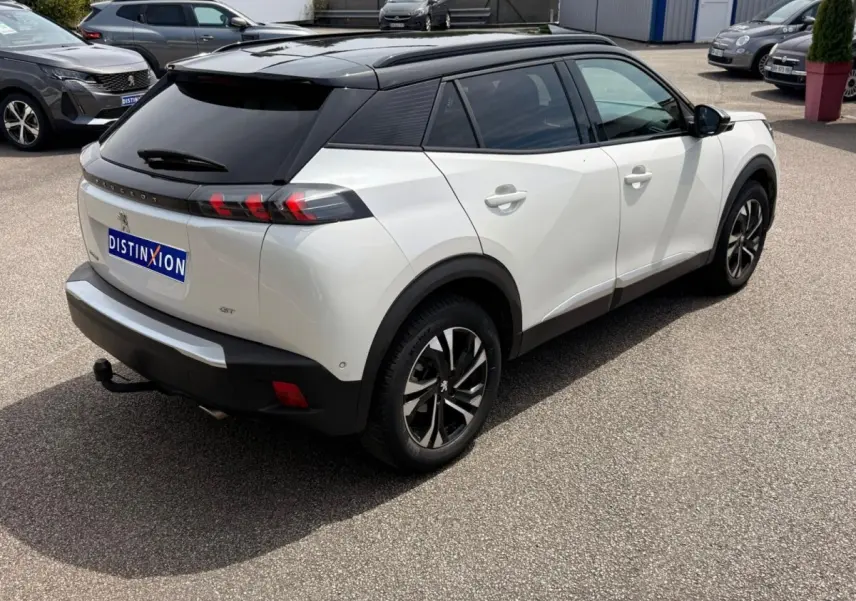Peugeot 2008 blanc en 3/4 arrière droit, toit noir contrasté et feux arrière à effet griffes rouges.