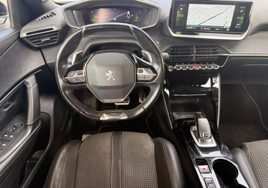 Vue intérieure frontale du poste de conduite du Peugeot 2008 GT 2021 avec volant compact, écran tactile et sellerie tri-matière noire.