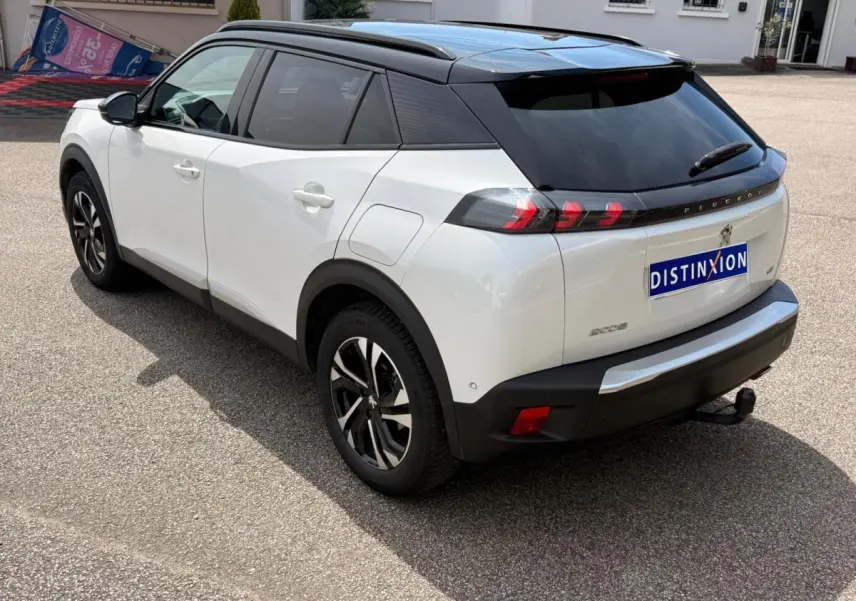 Vue 3/4 arrière droite d’un Peugeot 2008 blanc 2021 avec toit noir, feux arrière à LED et attelage visible.