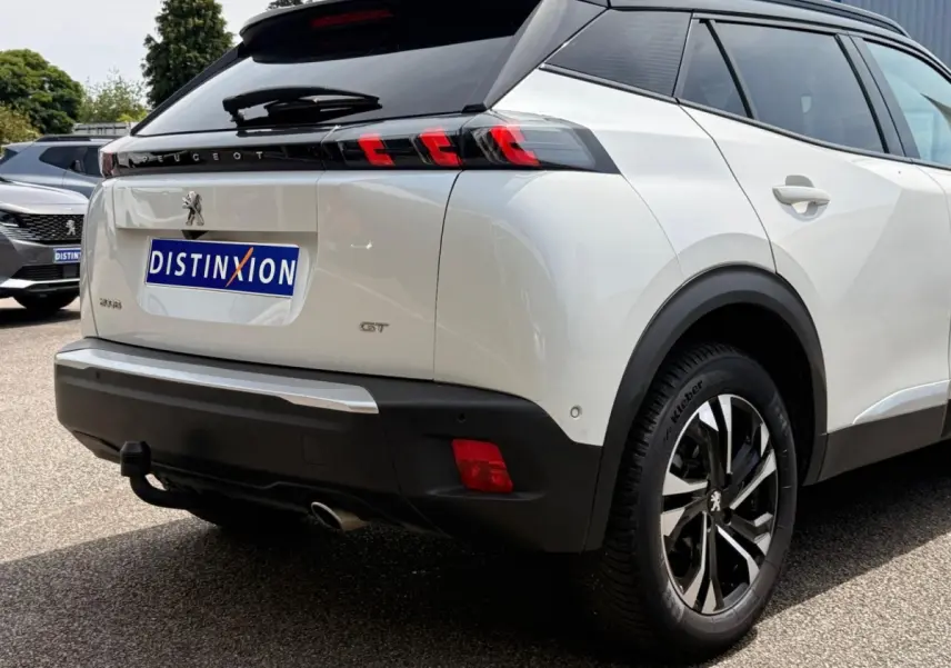 Vue 3/4 arrière droite du Peugeot 2008 blanc avec toit noir, feux arrière à LED et attelage visible.