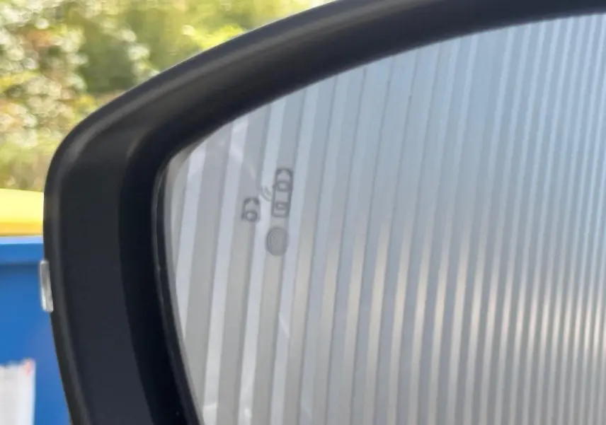 Rétroviseur extérieur gauche du Peugeot 2008 blanc, avec icônes d'alerte d'angle mort visibles sur le miroir.