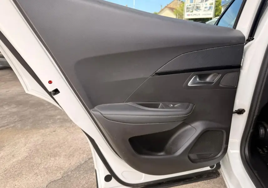 Vue rapprochée de la porte arrière droite blanche d’un Peugeot 2008 2021 avec garniture intérieure noire et surpiqûres grises.