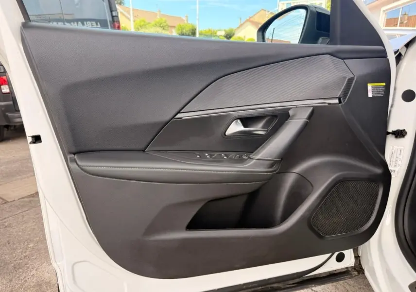 Vue intérieure côté gauche de la porte avant blanche du Peugeot 2008 avec garniture noire et surpiqûres vertes.