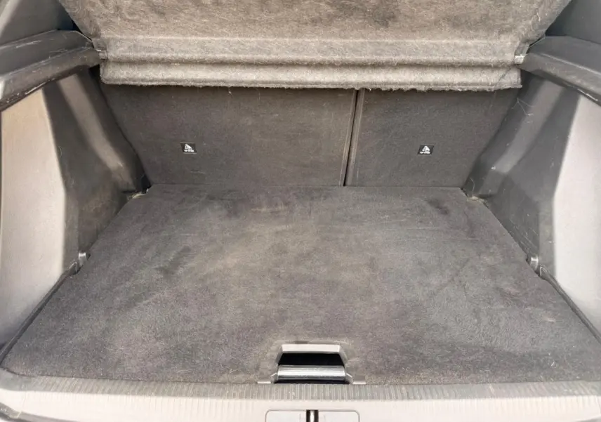 Coffre ouvert du Peugeot 2008 blanc, vue intérieure montrant le tapis de sol et la banquette arrière rabattue.