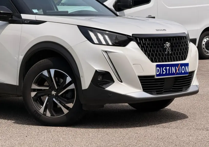 Vue 3/4 avant droit du Peugeot 2008 blanc avec calandre noire et jantes alliage bicolores.