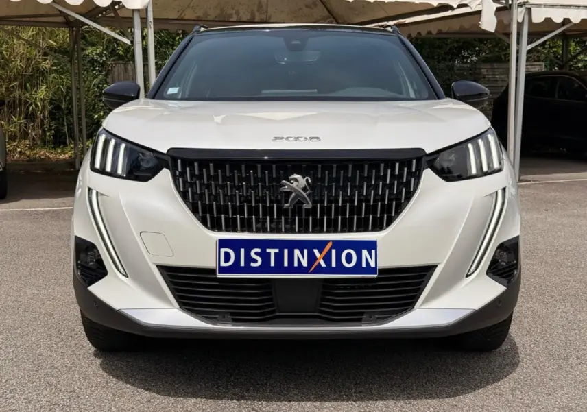 Vue avant d'un Peugeot 2008 blanc de 2021 avec calandre noire et feux LED verticaux distinctifs.