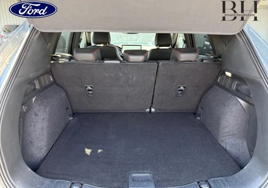 Coffre ouvert du Ford Kuga 2024 gris Solar, vue arrière montrant la banquette arrière et l'espace de chargement vide.
