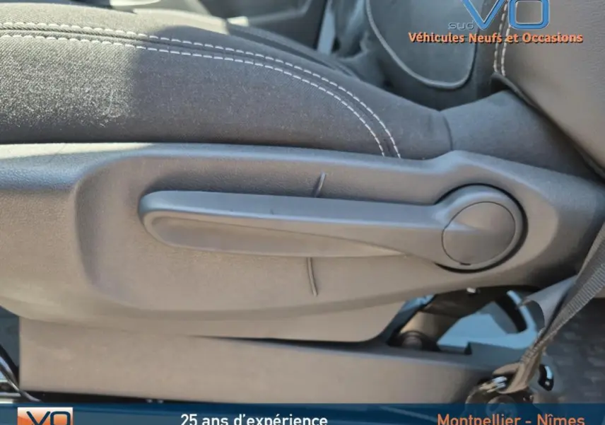 Levier de réglage manuel du siège avant en tissu noir avec surpiqûres blanches dans un Renault Trafic Fourgon gris foncé 2023.