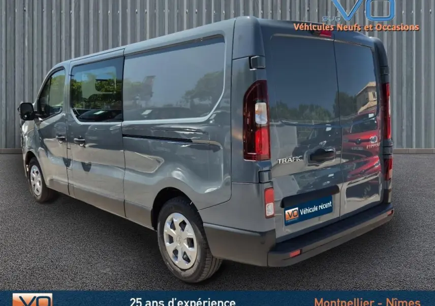 Renault Trafic Fourgon gris foncé vu en 3/4 arrière droit, avec porte latérale et vitres surteintées visibles.
