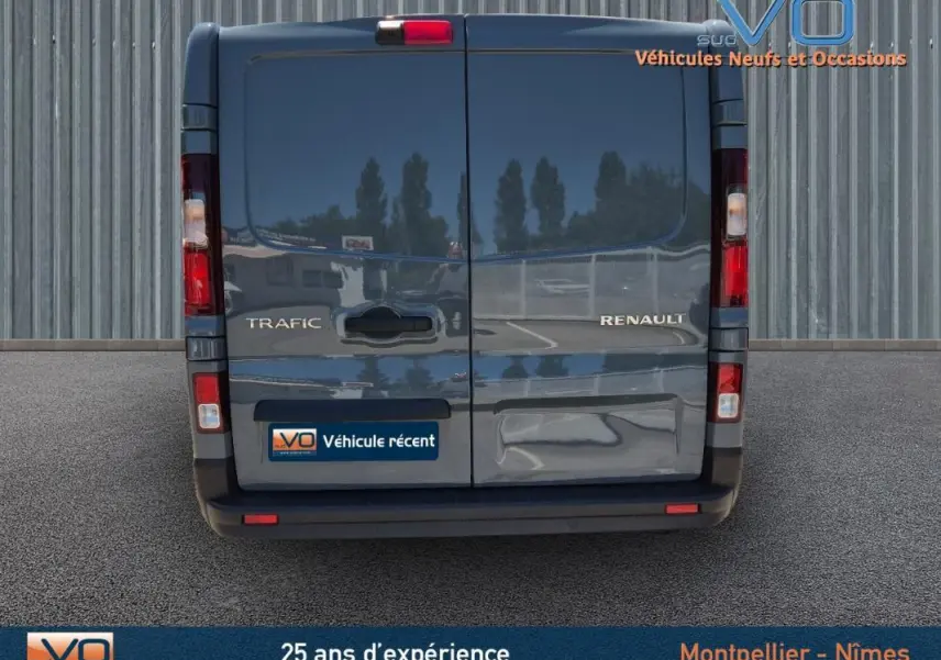 Vue arrière du Renault Trafic Fourgon gris foncé 2023 avec portes battantes et feux verticaux allumés.