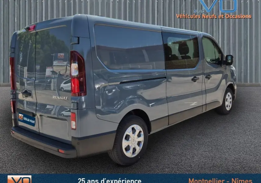 Vue 3/4 arrière droite d'un Renault Trafic Fourgon gris foncé avec porte latérale et vitres surteintées.