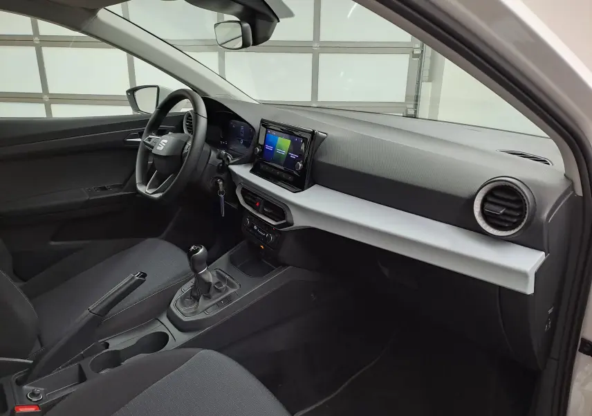 Vue intérieure côté conducteur de la SEAT Ibiza 2023 blanche, avec tableau de bord moderne et boîte manuelle visible.