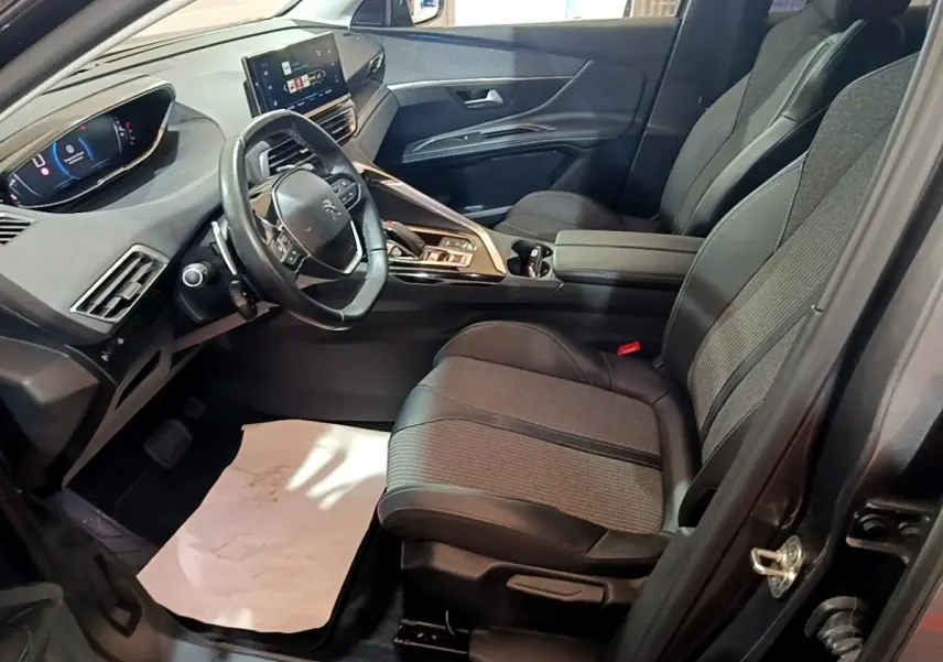 Intérieur avant droit du Peugeot 3008 gris foncé 2022, avec tableau de bord numérique et sièges tissu-cuir noirs.