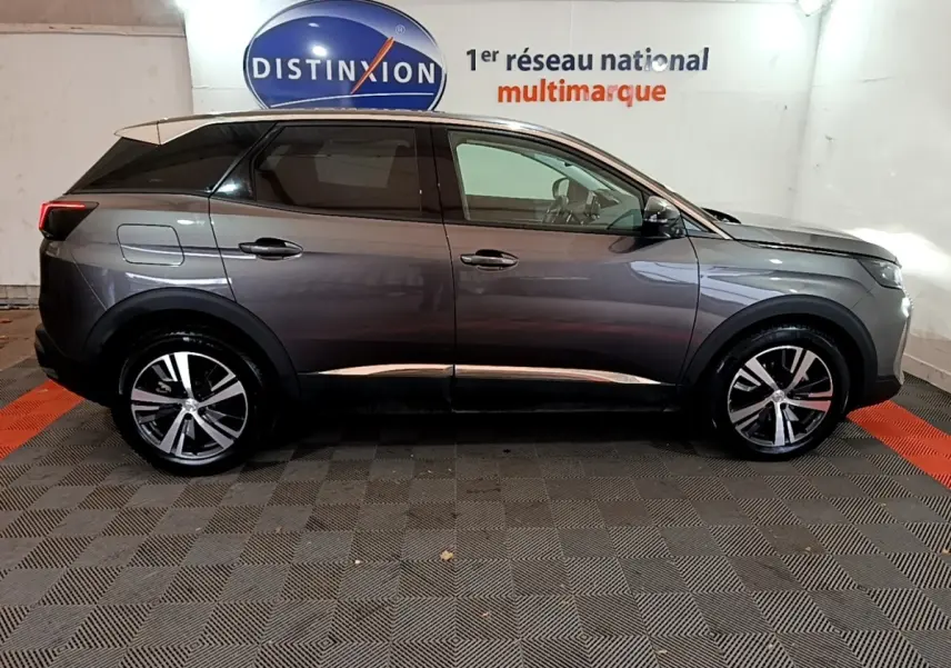 Profil côté droit du Peugeot 3008 gris foncé 2022 avec jantes alliage et vitres teintées dans un showroom.