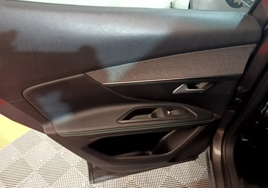 Gros plan sur la porte intérieure côté droit du Peugeot 3008 gris foncé, avec garniture cuir et surpiqûres vertes.