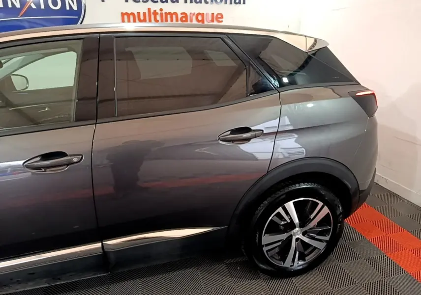 Vue latérale côté droit du Peugeot 3008 gris foncé avec jante alliage et vitres teintées en arrière-plan showroom.