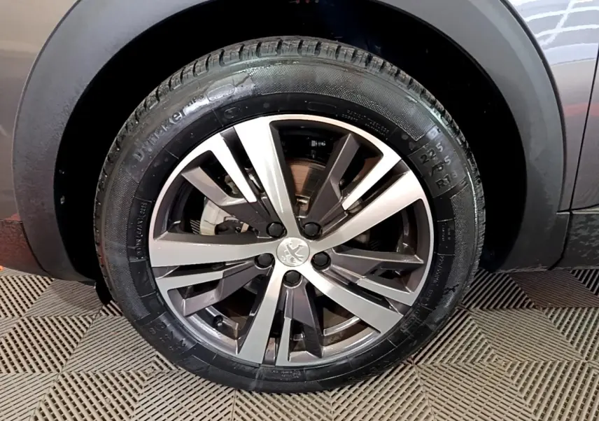 Gros plan sur la roue avant droite avec jante alliage du Peugeot 3008 gris foncé 2022.