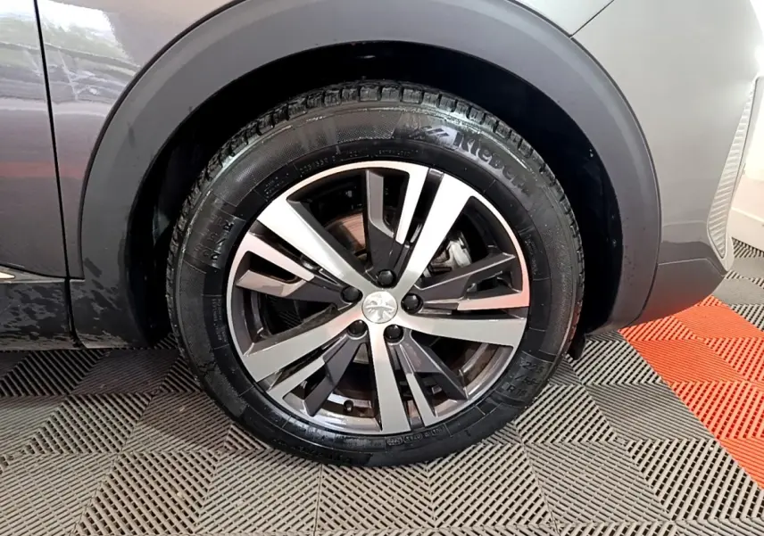 Gros plan sur la roue avant gauche du Peugeot 3008 gris foncé, mettant en valeur la jante alliage au design moderne.