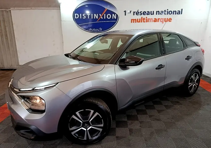 Vue 3/4 avant droite d'une Citroën C4 gris foncé avec phares allumés et jantes alliage distinctives.