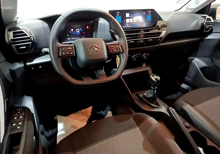 Vue intérieure avant de la Citroën C4 gris foncé 2021, volant multifonctions, écran tactile et boîte manuelle visible.