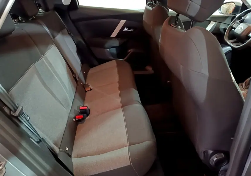 Vue intérieure côté arrière droit de la Citroën C4 gris foncé, montrant la banquette arrière et le volant multifonctions.