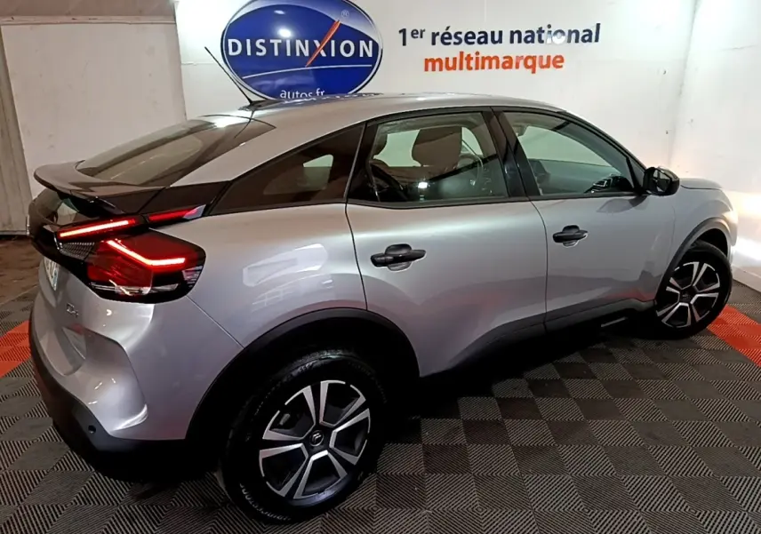 Vue 3/4 arrière droite d'une Citroën C4 gris foncé avec feux arrière LED allumés dans un showroom.