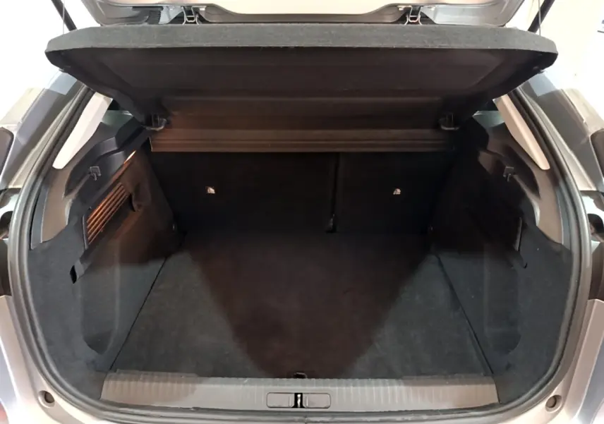 Coffre ouvert vu de l'arrière d'une Citroën C4 gris foncé, montrant l'espace de chargement vide et la tablette arrière.
