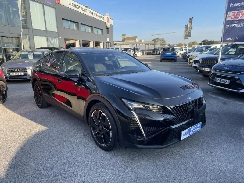 Peugeot 408 Hybrid 136 cv GT noir métal vue 3/4 avant droit, avec calandre distinctive et jantes noires sportives.