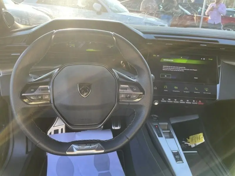 Vue intérieure centrée sur le volant GT du Peugeot 408 Hybrid 2024 avec tableau de bord digital et écran tactile.