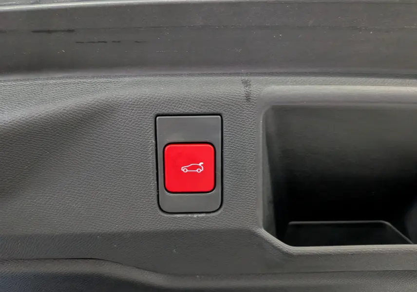 Bouton rouge d'ouverture électrique du coffre sur panneau intérieur noir d'un Peugeot 5008 HYBRID 145 GT.
