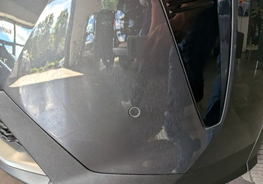 Gros plan sur l’avant droit gris titane du Peugeot 5008 Hybrid 145 GT avec capteur de stationnement circulaire visible.