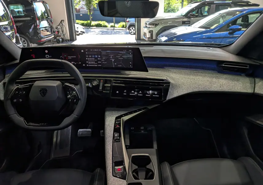 Vue intérieure avant du Peugeot 5008 Hybrid 145 GT 2025, tableau de bord moderne avec écran large et finition tissu gris.
