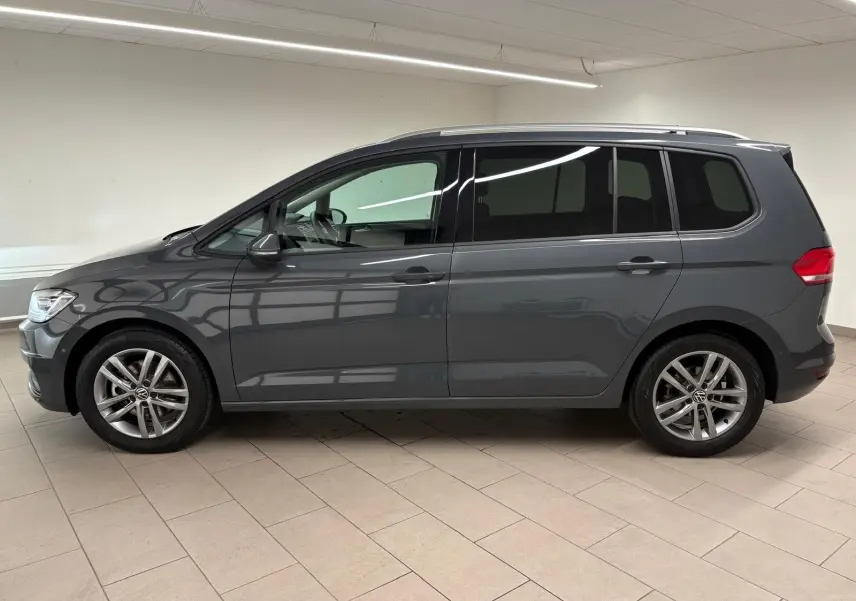 Profil droit d'un Volkswagen Touran 2025 gris dauphin avec jantes alliage et vitres teintées en intérieur neutre.