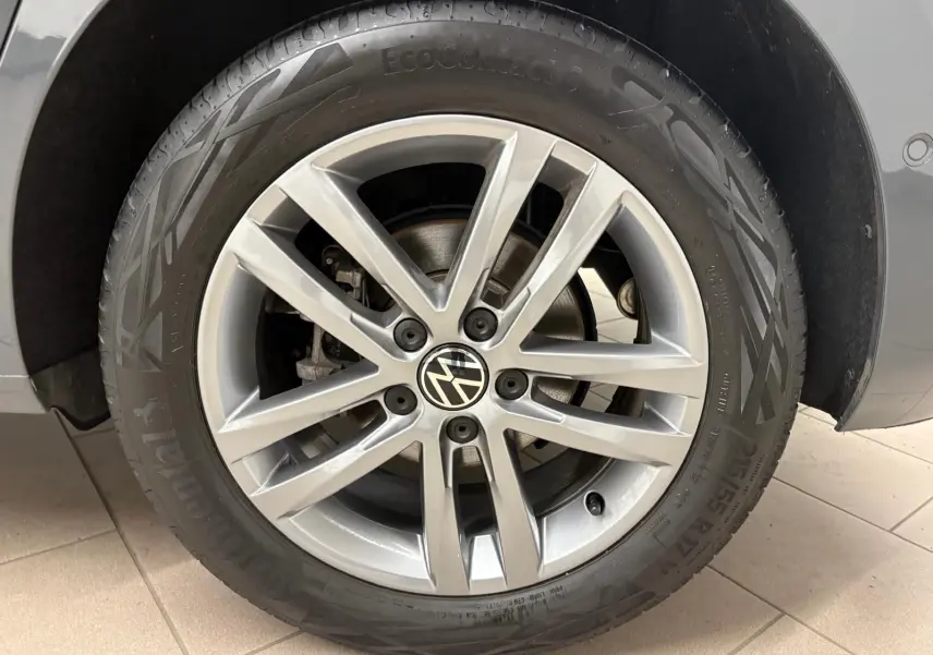 Gros plan sur la roue avant droite en alliage du Volkswagen Touran gris Dauphin, mettant en valeur le logo VW central.