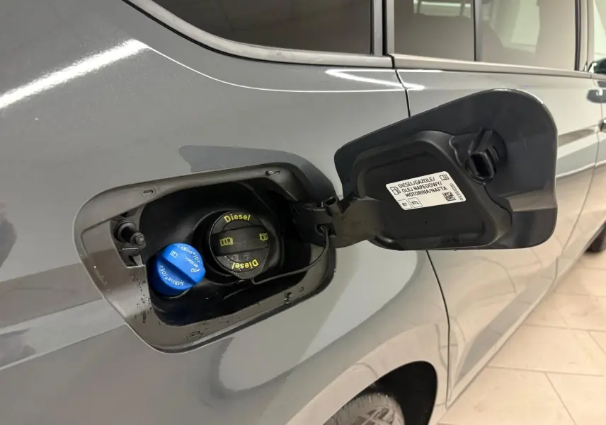 Gros plan sur la trappe à carburant côté gauche d’un Volkswagen Touran gris Dauphin avec bouchons Diesel et AdBlue visibles.