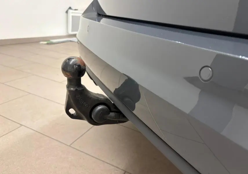 Gros plan sur l'attelage escamotable électrique du pare-chocs arrière gris dauphin du Volkswagen Touran 2025.