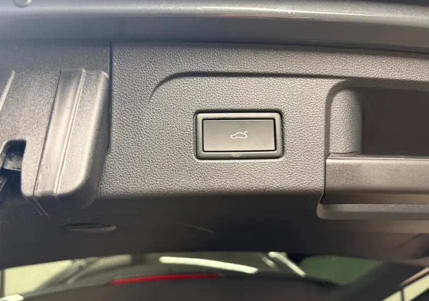 Bouton d'ouverture électrique du hayon sur la partie intérieure du coffre du Volkswagen Touran gris dauphin.