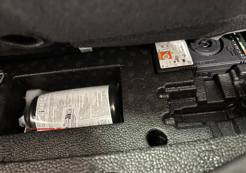 Rangement sous plancher de coffre avec kit de réparation pneu dans un Volkswagen Touran 2025 gris Dauphin.