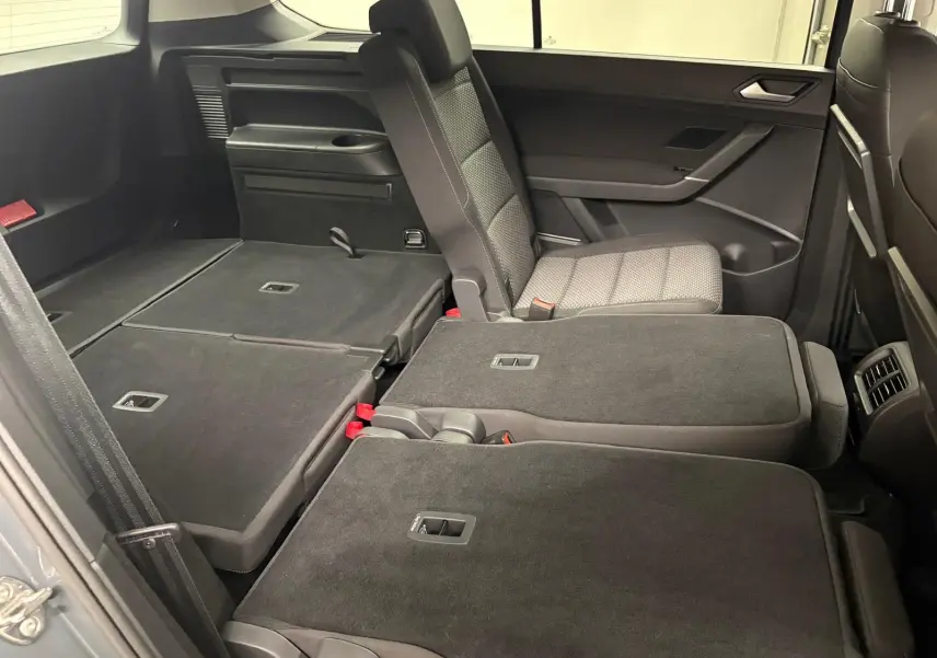 Vue intérieure côté droit du Volkswagen Touran 2025, sièges arrière partiellement rabattus avec sellerie grise.
