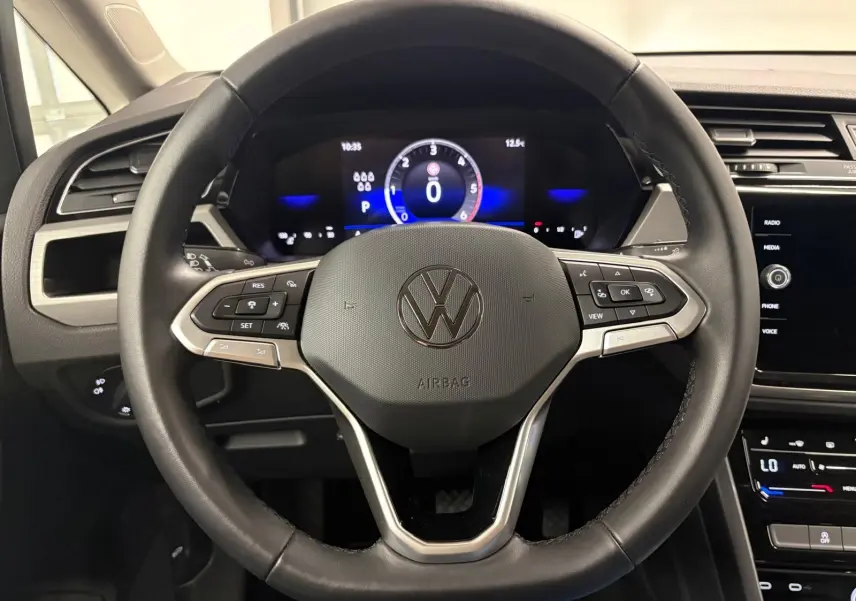 Vue frontale du volant cuir noir du Volkswagen Touran 2025 avec tableau de bord numérique et commandes intégrées.
