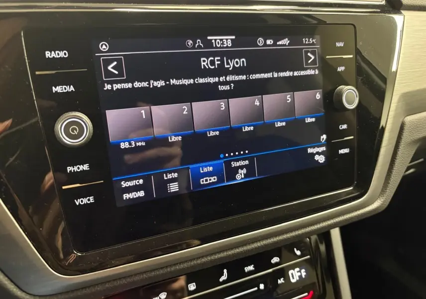 Écran tactile central du Volkswagen Touran 2025 affichant la radio RCF Lyon, avec commandes autour et finition intérieure noire.