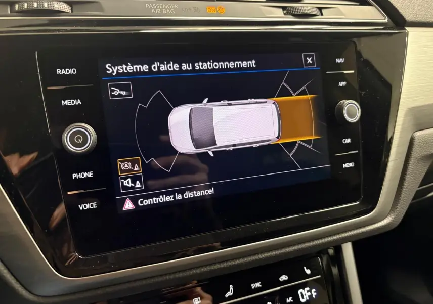 Écran central du Volkswagen Touran 2025 affichant le système d'aide au stationnement avec visualisation du véhicule vue de dessus.
